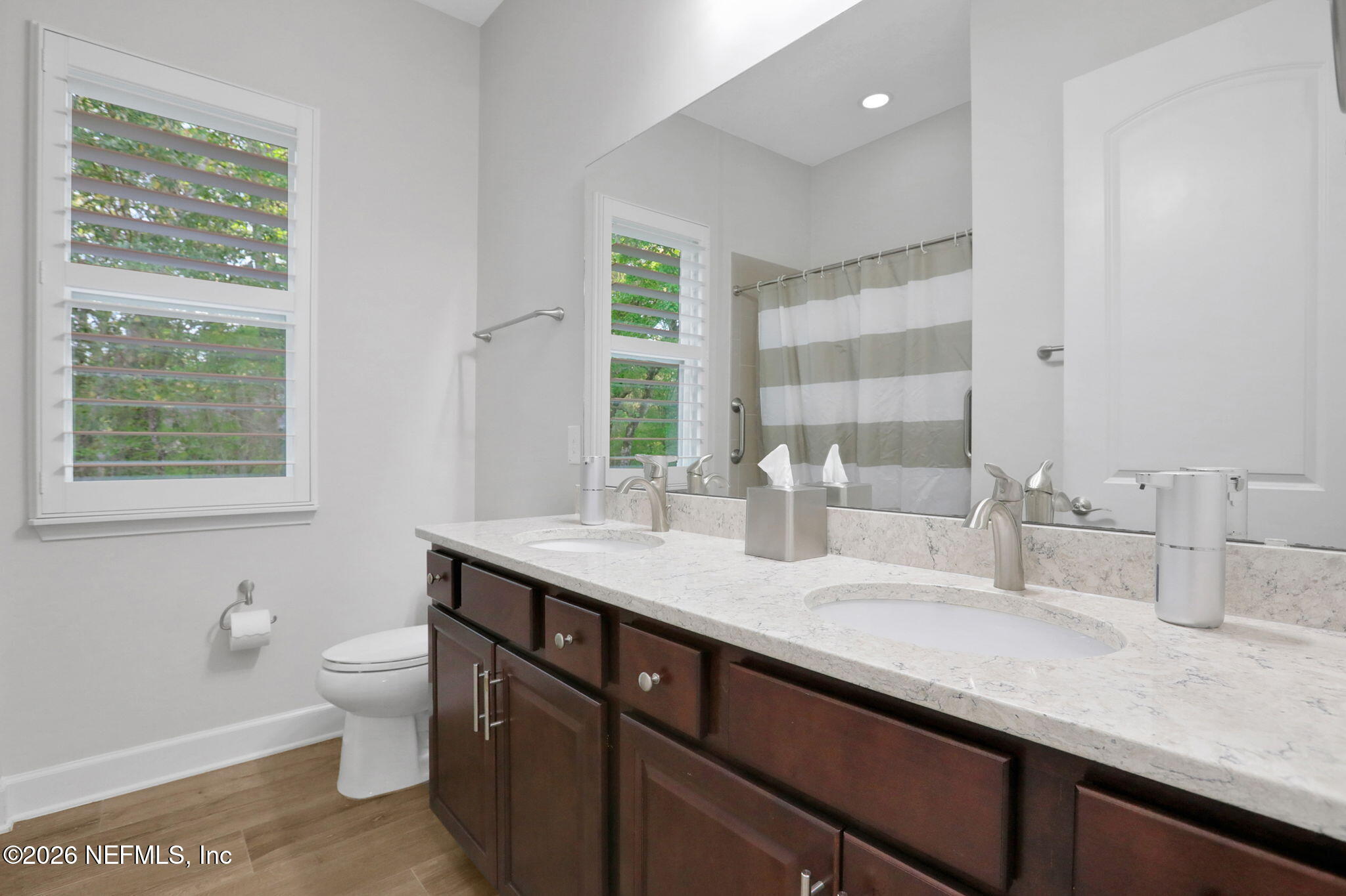 4460 Barkoskie Road Jacksonville, FL 32258 - Photo 42 of 80 a bathroom with a granite countertop sink a toilet a mirror and a window