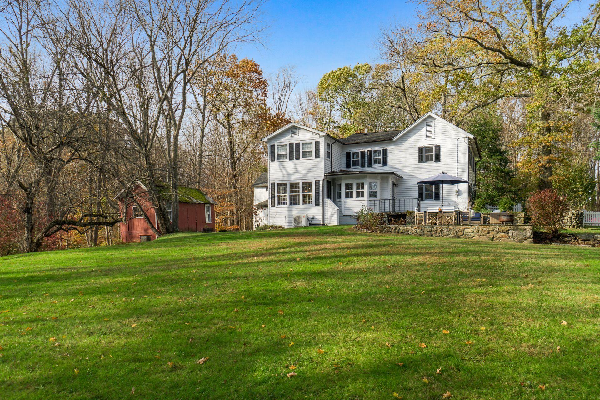 1122 Smith Ridge Road New Canaan, CT 06840 - Photo 17 of 25 a view of a big house with a big yard and large trees