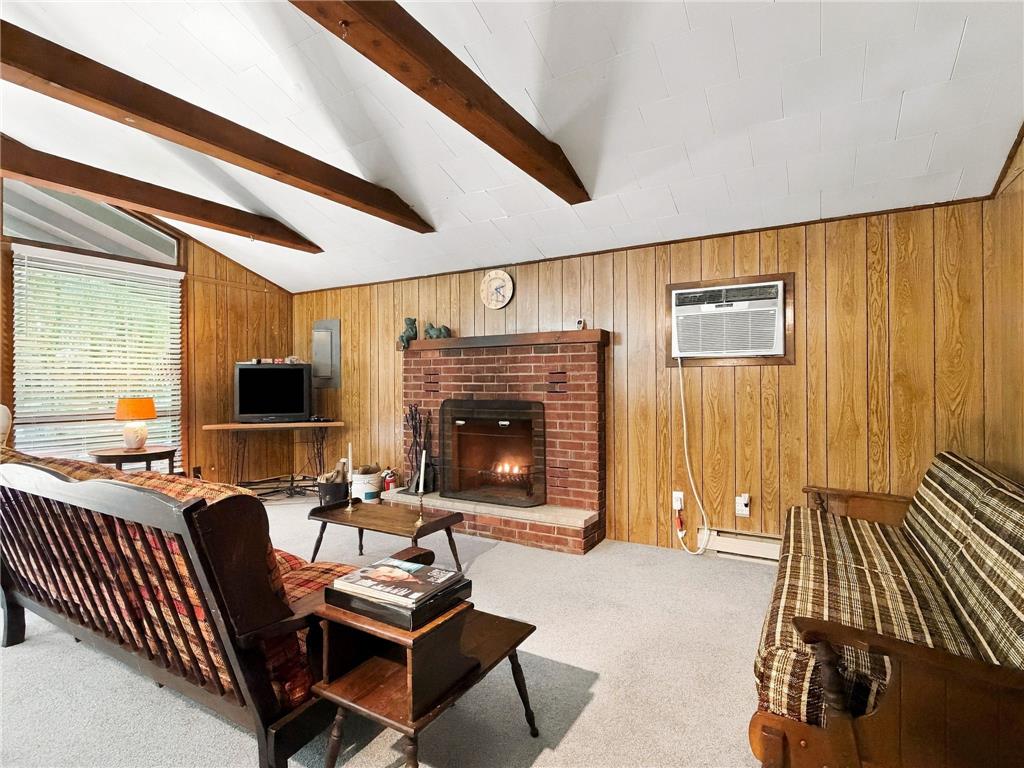 116 Aspen Road Albrightsville, PA 18210 - Photo 12 of 33 Exposed wood beams and a classic brick fireplace anchor this cozy living room space.