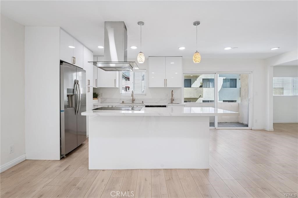 a large white kitchen with kitchen island a large counter top a sink stainless steel appliances and cabinets