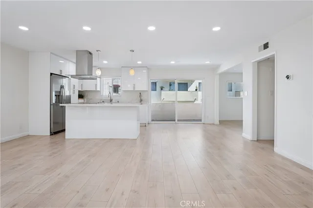 a large white kitchen with stainless steel appliances lots of counter space and a wooden floor