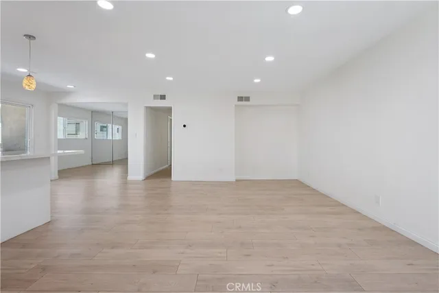 a view of an empty room with wooden floor and windows
