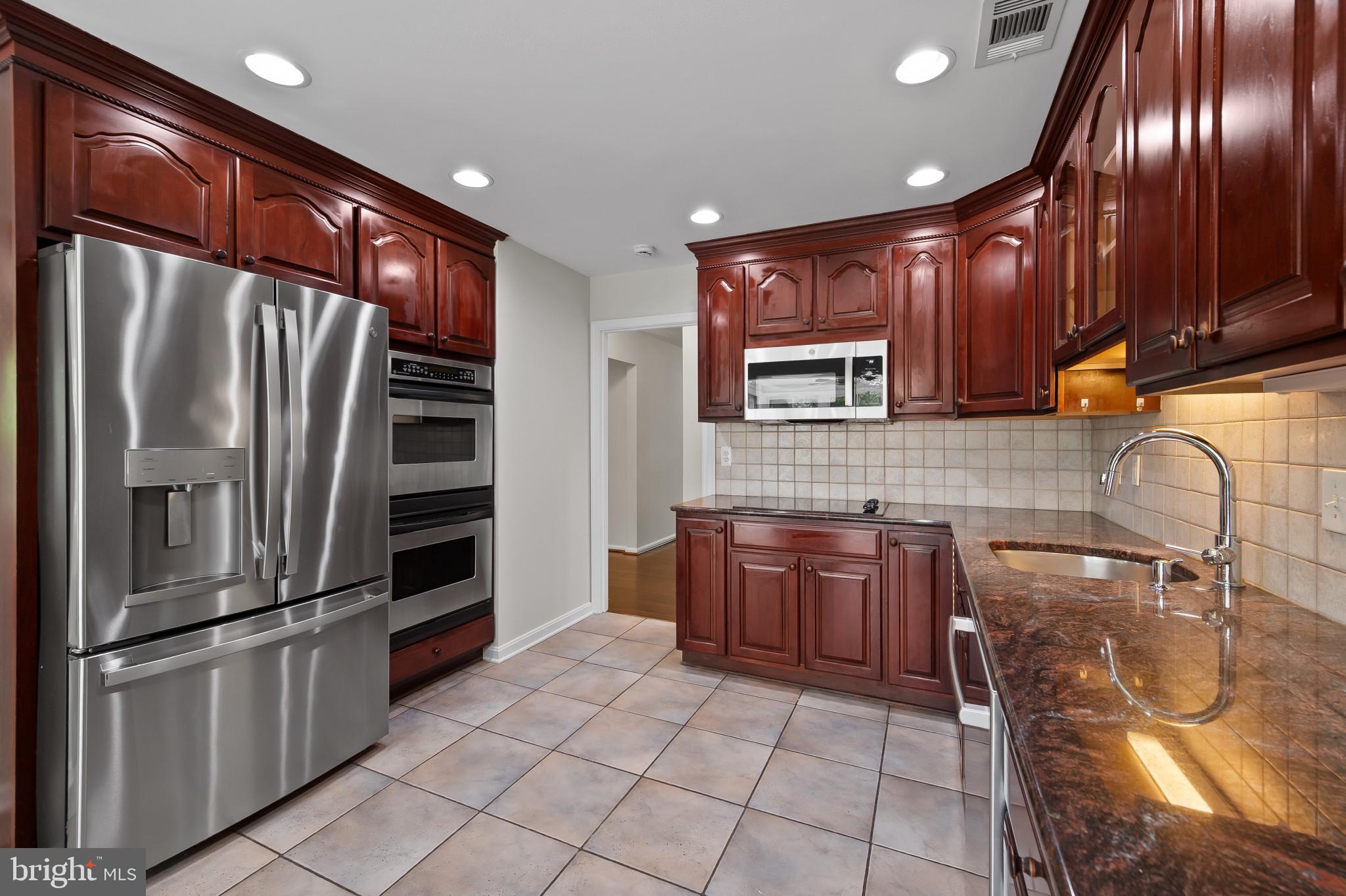 15016 Wellwood Road Silver Spring, MD 20905 - Photo 9 of 52 a kitchen with granite countertop stainless steel appliances and wooden cabinets