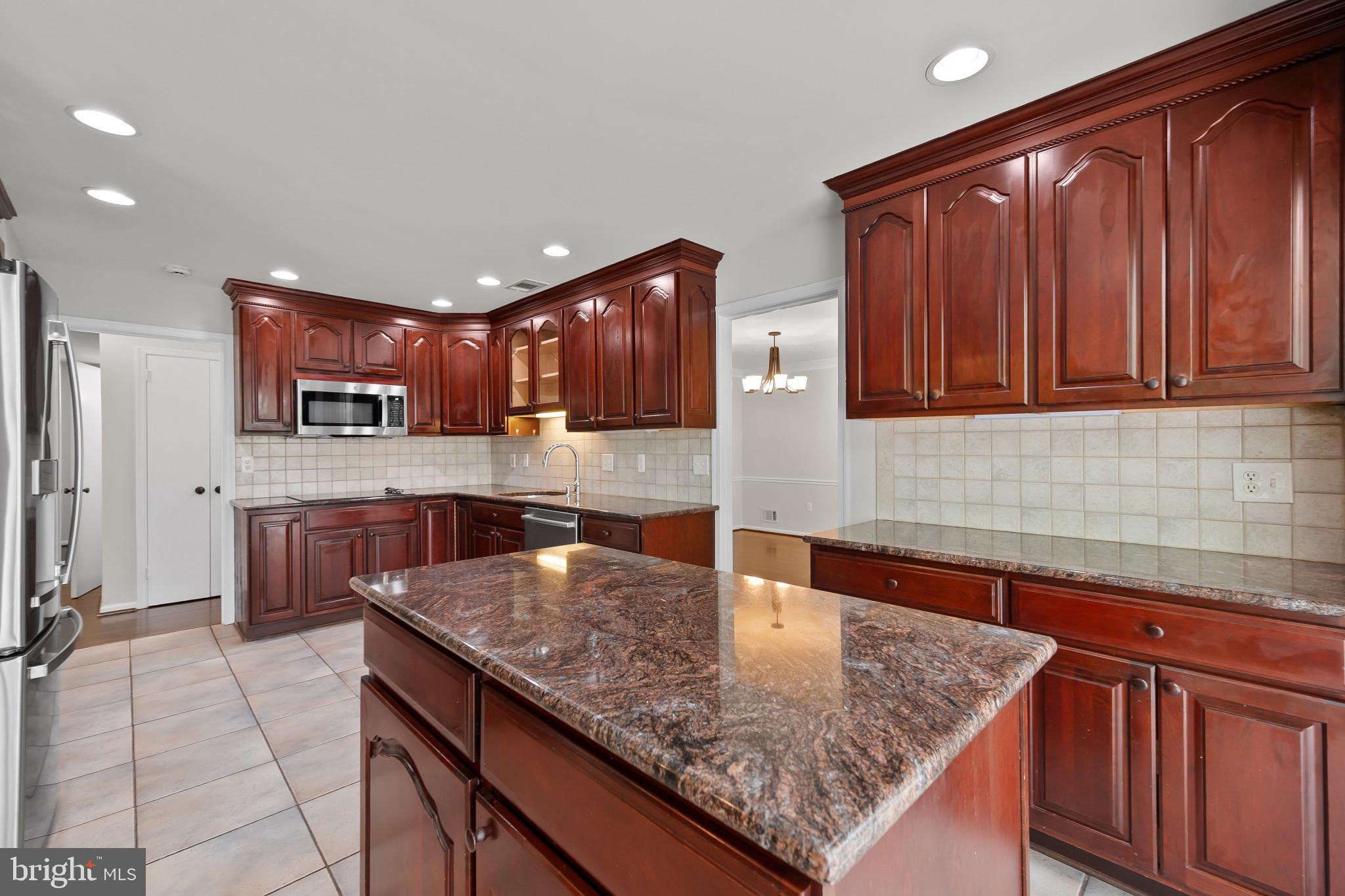 15016 Wellwood Road Silver Spring, MD 20905 - Photo 10 of 52 a kitchen with stainless steel appliances granite countertop a sink a microwave and wooden cabinets