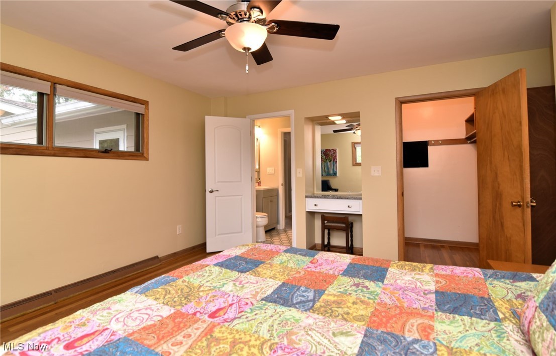 2071 Wyndham Road Akron, OH 44313 - Photo 16 of 42 Primary bedroom with ceiling fan, ensuite bath, a walk-in closet, wood floors and built in dressing table.