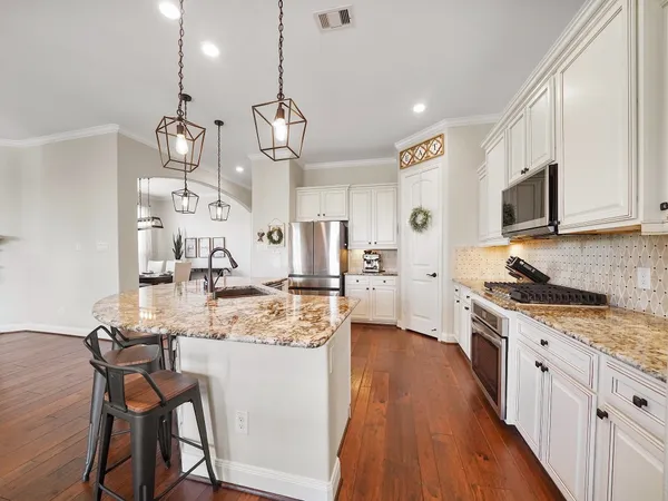 a kitchen with stainless steel appliances kitchen island granite countertop a sink cabinets and wooden floor