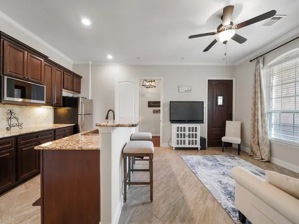 a living room with furniture a flat screen tv and kitchen view