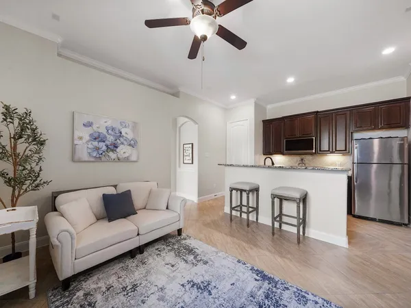 a living room with stainless steel appliances furniture a flat screen tv and a dining table