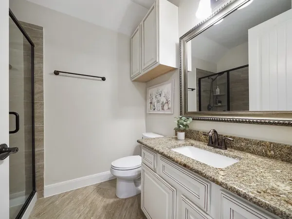 a bathroom with a granite countertop sink toilet and shower