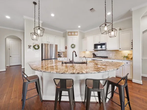 a kitchen with kitchen island granite countertop a dining table chairs and cabinets