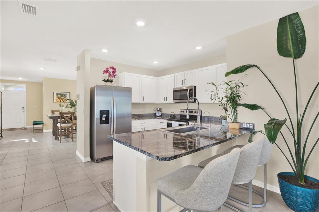 16034 Tuscany Hillside Road Odessa, FL 33556 - Photo 10 of 48 a kitchen with stainless steel appliances granite countertop a refrigerator a sink a stove a dining table and chairs