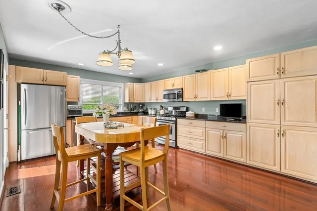 a kitchen with stainless steel appliances granite countertop a refrigerator a stove top oven a sink dishwasher and white cabinets with wooden floor