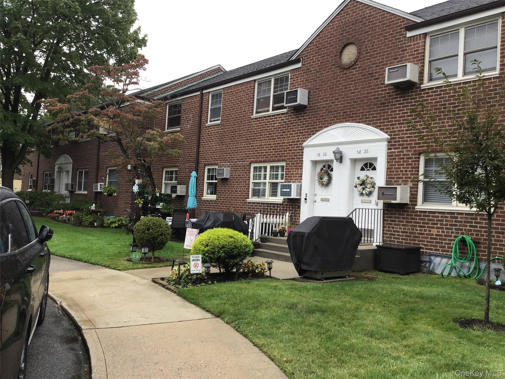 View of front of property with a front lawn, brick siding, and a wall mounted air conditioner