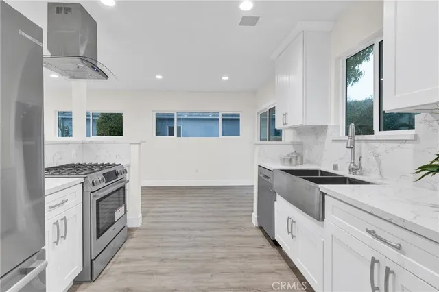 a kitchen with granite countertop a sink a counter top space stainless steel appliances and cabinets