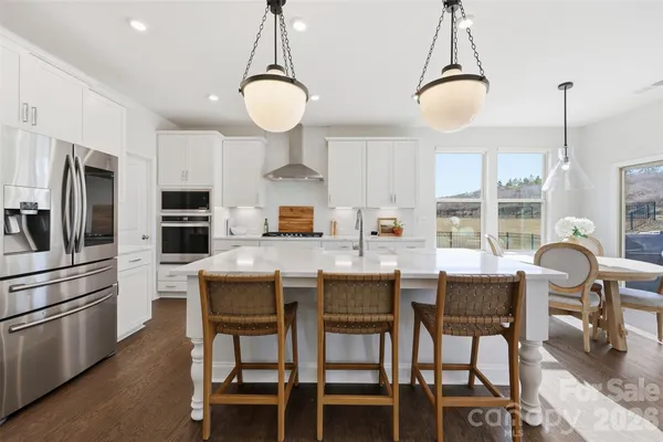 a kitchen with granite countertop a table chairs stove and microwave