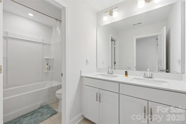 a bathroom with a double vanity sink toilet mirror and bathtub