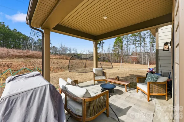 a living room with patio furniture and a floor to ceiling window next to a yard