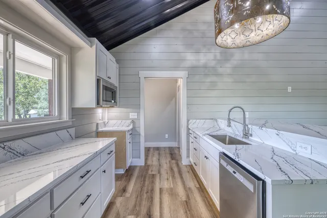 a kitchen with granite countertop a sink stainless steel appliances a counter space and cabinets
