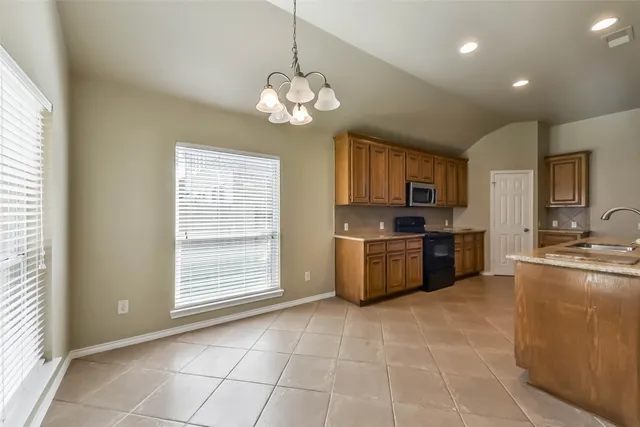 a large kitchen with stainless steel appliances granite countertop a stove top oven a sink dishwasher a dining table and chairs with wooden floor