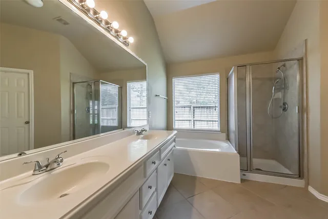 a spacious bathroom with a tub sink shower and mirror