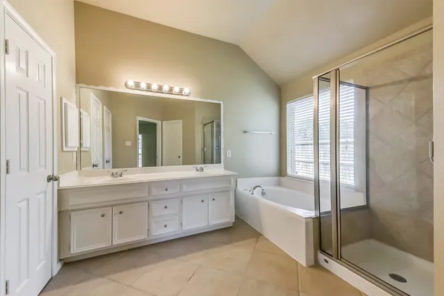 a spacious bathroom with a double vanity sink a large mirror and a bathtub