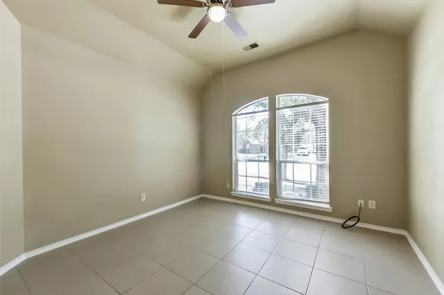 an empty room with windows and ceiling fan