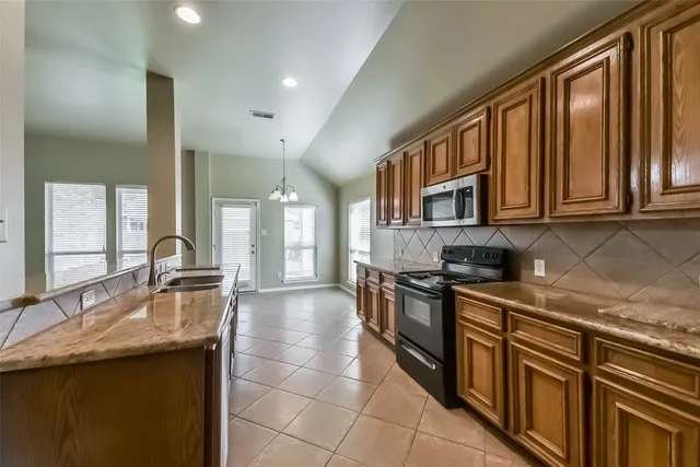 a kitchen with stainless steel appliances granite countertop a sink stove and cabinets