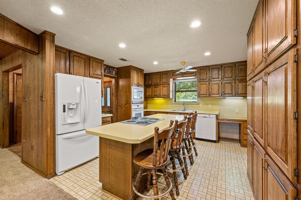 515 New Highland Road Springtown, TX 76082 - Photo 12 of 38 Kitchen featuring extensive wood cabinetry, a central island with an integrated cooktop and seating, double ovens, and recessed lighting