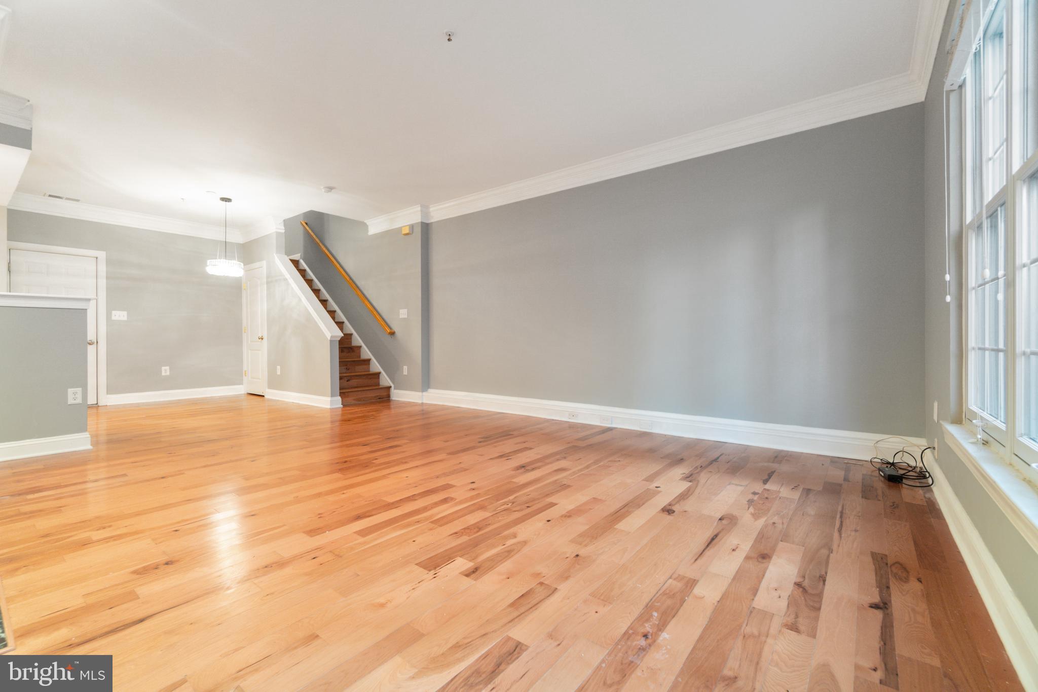 104 Bucksfield Road, Unit 104 Gaithersburg, MD 20878 - Photo 3 of 39 a view of an empty room with wooden floor and a window