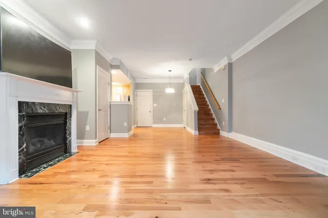 a view of an empty room with wooden floor fireplace and a window