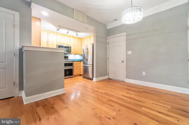 an empty room with wooden floor kitchen view and a window