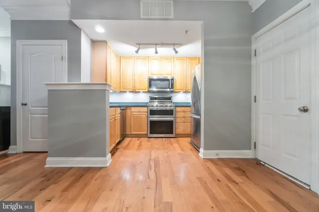 an empty room with wooden floor kitchen view and a window