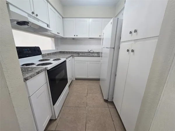 a kitchen with a stove top oven and white cabinets