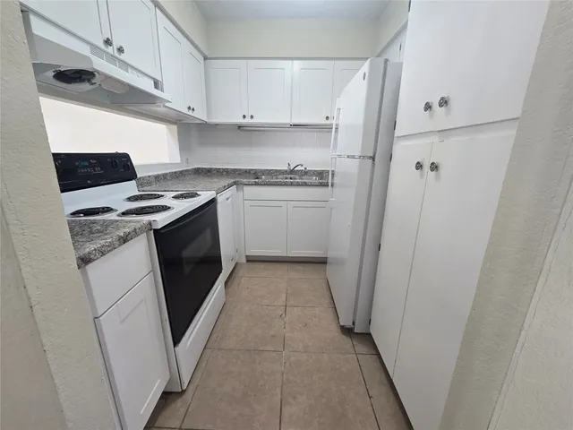 a kitchen with a stove top oven and white cabinets
