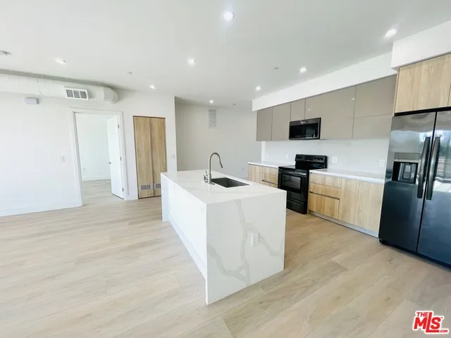 a living room with stainless steel appliances furniture a flat screen tv and a refrigerator