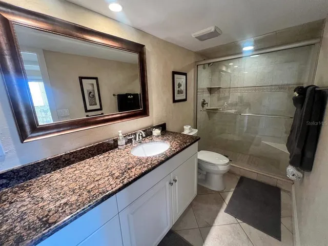 a bathroom with a granite countertop sink toilet and mirror