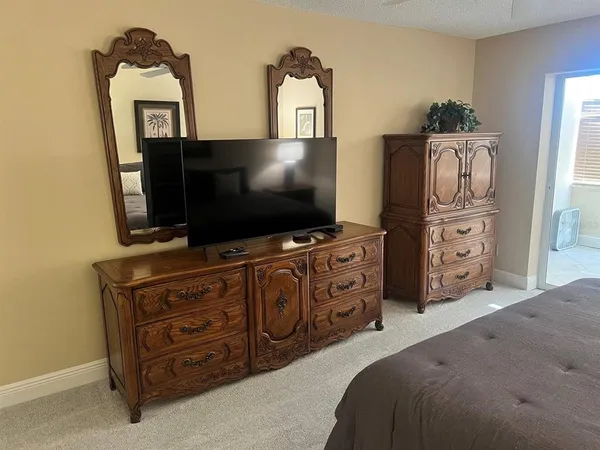 a bedroom with a bed and a flat tv screen on dresser