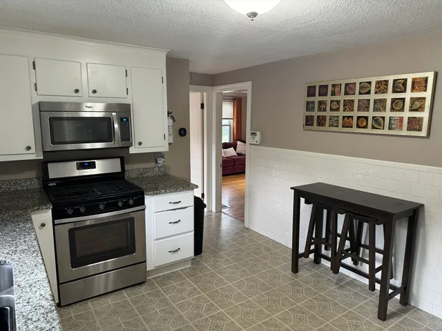 a kitchen with granite countertop a stove and a microwave