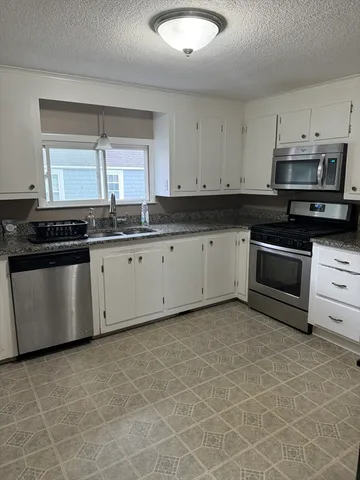 a kitchen with stainless steel appliances granite countertop a stove a sink and a microwave
