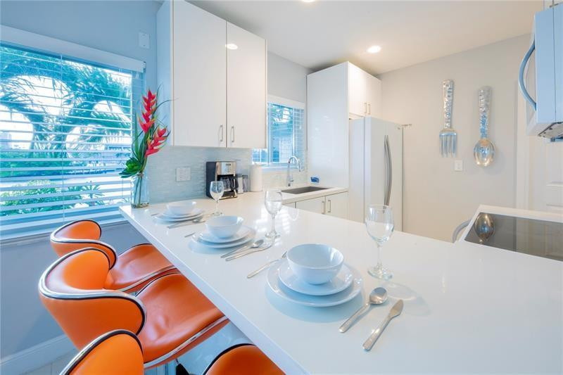 1705 North Riverside Drive, Unit 5 Pompano Beach, FL 33062 - Photo 8 of 24 a kitchen with stainless steel appliances kitchen island granite countertop a dining table and chairs