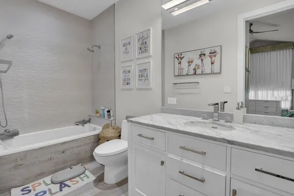 a bathroom with a granite countertop sink toilet a large mirror a bathtub and a shower
