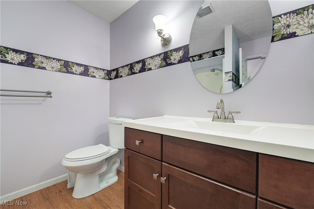 1820 Claus Road Vermilion, OH 44089 - Photo 9 of 10 Bathroom with vanity, toilet, hardwood / wood-style floors, and a textured ceiling