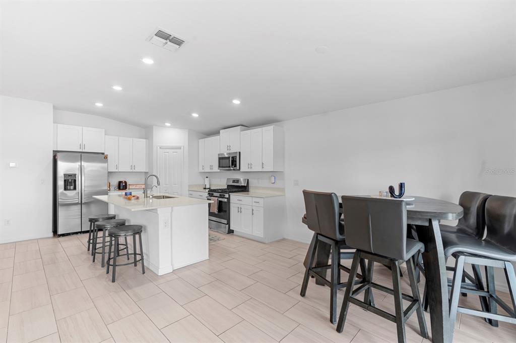 13124 Merlot Sunstone Cove Parrish, FL 34219 - Photo 25 of 45 a kitchen with a dining table chairs and refrigerator