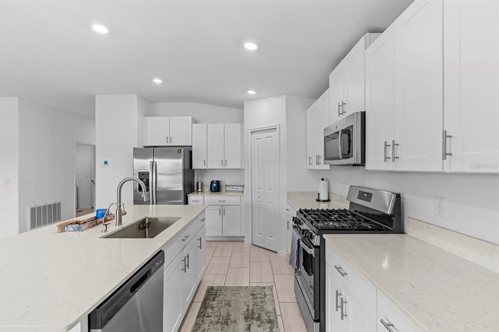 13124 Merlot Sunstone Cove Parrish, FL 34219 - Photo 26 of 45 a kitchen with stainless steel appliances a sink a stove a refrigerator a center island and cabinets