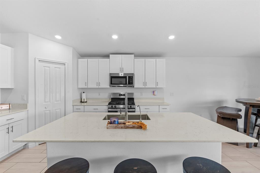 13124 Merlot Sunstone Cove Parrish, FL 34219 - Photo 29 of 45 a kitchen with kitchen island granite countertop a sink a stove and a refrigerator