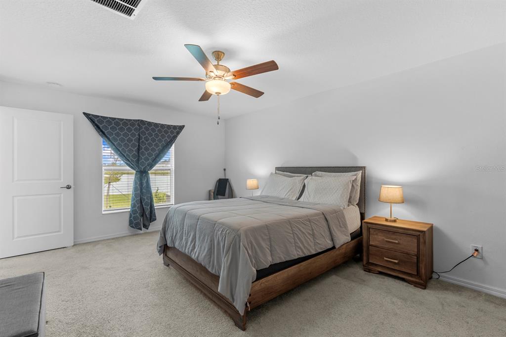 13124 Merlot Sunstone Cove Parrish, FL 34219 - Photo 34 of 45 a bedroom with a bed next to a window and a chandelier