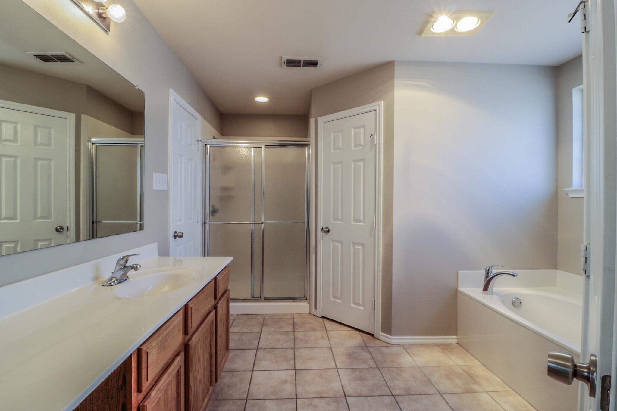 6808 88th Street Lubbock, TX 79424 - Photo 15 of 17 a bathroom with a tub sink shower and mirror