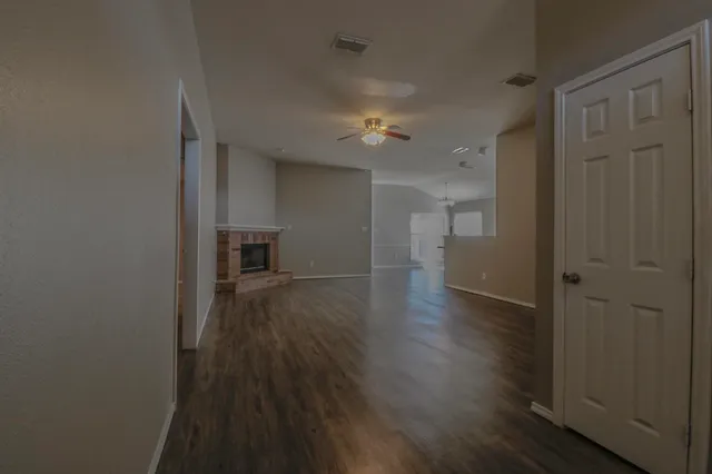 a view of a hallway with wooden floor and a bathroom