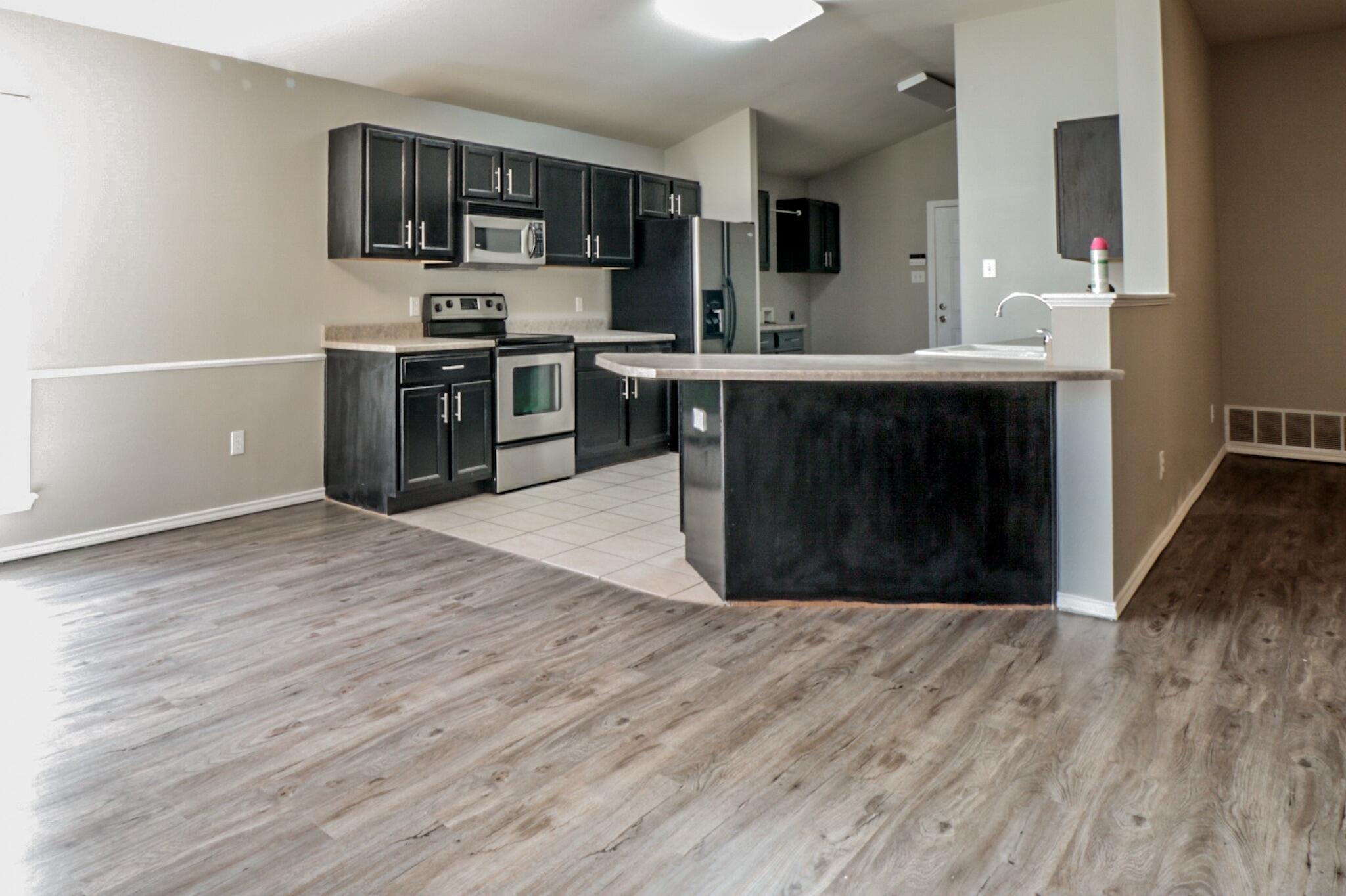 6808 88th Street Lubbock, TX 79424 - Photo 3 of 17 a kitchen with stainless steel appliances a sink cabinets and wooden floor