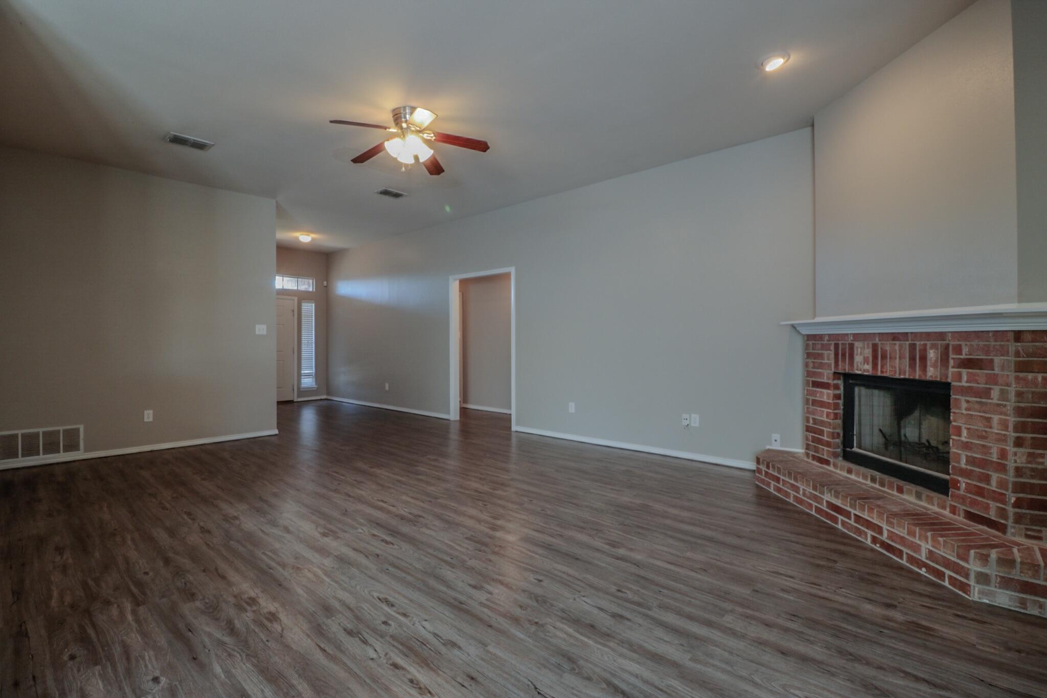 6808 88th Street Lubbock, TX 79424 - Photo 7 of 17 a view of an empty room with wooden floor fireplace and a window